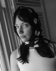 Woman wearing a black silk square scarf with white polka dots around the head, a handmade silk scarf by nessi, an Australian independent fashion label.