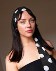 Woman wearing a black silk skinny scarf with white polka dots tied as a headband, a handmade silk scarf by nessi, an Australian independent fashion label.