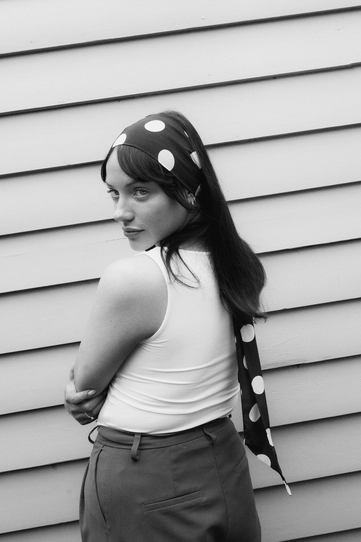 Woman wearing a black silk skinny scarf with white polka dots tied as a headband, a handmade silk scarf by Nessi, an Australian independent fashion label.